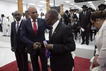 Haiti’s outgoing President Michel Martelly (2L) shakes hands with the Senate President Jocelerme Privert (C) in presence of the Prime Minister Evans Paul during a ceremony marking the end of Martelly’s presidential term, in the Haitian Parliament in Port-au-Prince, Haiti yesterday. REUTERS/Andres Martinez Casares