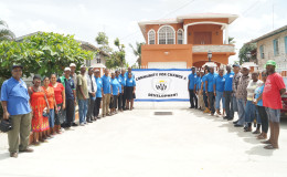Members of Community for Change and Development pose for a photo. The group’s banner is displayed in the background. 