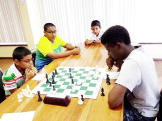 During the Trophy Stall chess tournament, the youths demonstrated an appreciation for each other’s games by sometimes physically supporting their colleagues. In this photograph, University of Guyana geological engineering second year student Owen Mickle (right) playing the white chess pieces, takes on Ghansham Allijohn of St Stanislaus College. The two onlookers are Kristoff Prashad with glasses and John Wong. The entire entourage has its roots in the robust St. Stanislaus College’s Chess Club. 