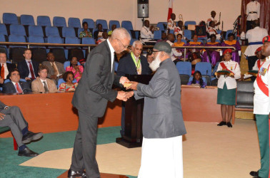 Mohamod Mujay (right) receives the Medal of Service for outstanding work by the Guyana Islamic Trust in the area of Education from President David Granger. (Ministry of the Presidency photo)