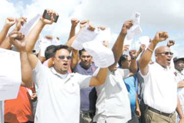 Former employees of Centrin display their dismissal letters outside the company’s compound, Point Lisas, Couva, on Thursday, where they called on Prime Minister Dr Keith Rowley to intervene on their behalf. 