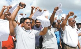 Former employees of Centrin display their dismissal letters outside the company’s compound, Point Lisas, Couva, yesterday, where they called on Prime Minister Dr Keith Rowley to intervene on their behalf. 