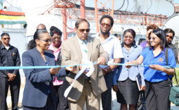 Prime Minister Moses Nagamootoo assisted by NCN’s Chief Executive Officer, Molly Hassan cut the ceremonial ribbon to commission the Satellite Earth Station Multimedia Teleport at National Communications Network (NCN). (Government Information Agency photo)