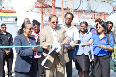 Prime Minister Moses Nagamootoo assisted by NCN’s Chief Executive Officer, Molly Hassan cut the ceremonial ribbon to commission the Satellite Earth Station Multimedia Teleport at National Communications Network (NCN). (Government Information Agency photo)