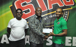 EBFA President Franklin Wilson (centre) receiving the sponsorship cheque from Stag Beer Brand Representative Lindon Henry following the launch of the EBFA Stag Beer 1st division league yesterday at the Ansa McAl boardroom.