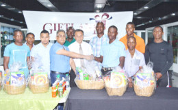 CEO of the Giftland Mall, Roy Beepat (left) hands over one of the hampers to Diwani Lampkin on Tuesday at the Pattensen edifice.