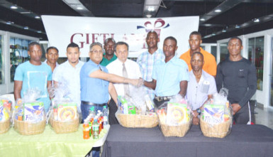 CEO of the Giftland Mall, Roy Beepat (left) hands over one of the hampers to Diwani Lampkin on Tuesday at the Pattensen edifice. 