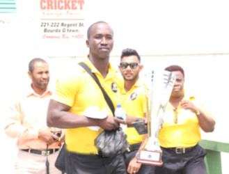 Guyana Jaguars assistant head Rayon Griffith poses with the Regional Four Day trophy yesterday prior to the team’s departure for Antigua. 
