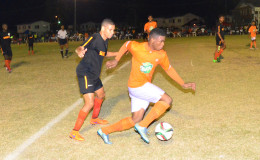 Eon Alleyne of Fruta Conquerors trying to maintain possession of the ball while being challenged by his Slingerz FC marker during their fixture in the GFF Elite League Friday night .