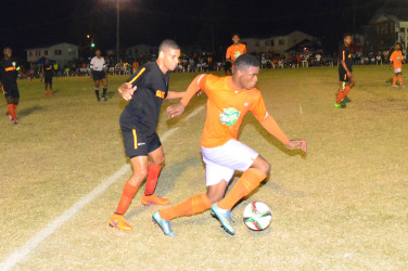 Eon Alleyne of Fruta Conquerors trying to maintain possession of the ball while being challenged by his Slingerz FC marker during their fixture in the GFF Elite League Friday night .