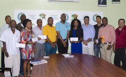 Director of Sport, Christopher Jones (centre) with the beneficiaries of the monies disbursed yesterday at the National Sports Commission. (Orlando Charles photo)