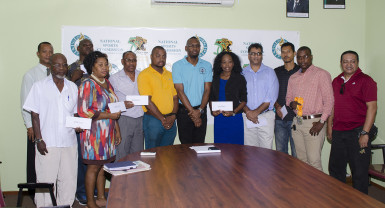 Director of Sport, Christopher Jones (centre) with the beneficiaries of the monies disbursed yesterday at the National Sports Commission. (Orlando Charles photo) 