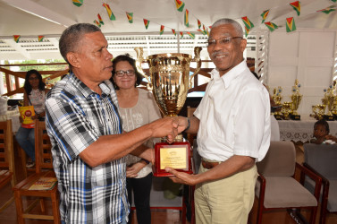 President David Granger (right) presents Region Seven Chairman,  Gordon Bradford with the Champion’s Trophy for the winner of this year’s races. First Lady Sandra Granger is at centre. (Ministry of the Presidency photo)