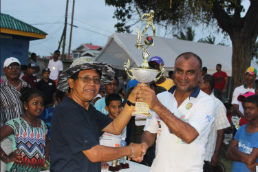 Clement Edwards, left, head master of Crabwook Creek Primary School, hands over the Mohan and Meena Memorial Trophy to Floodlights Legends skipper Ricky Deonarain.