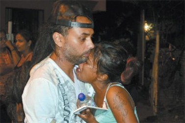 Shayas Khan, left, comforts his wife, Vishma Bissoon, outside their home at Jameel Street, Charlieville, following the death of the couple’s six-month-old son, Maleek Khan, yesterday.