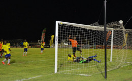Julian Wade (orange) of Slingerz FC netting his team’s second goal while being challenged by two Pele players during their GFF Elite League matchup at the Leonora Sports Facility