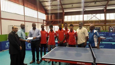 Former national table tennis player Garfield Wiltshire, treasurer of the Guyana Olympic Association (GOA) hands over the sponsorship cheque to president of the Guyana Table Tennis Association (GTTA) Godfrey Munroe. At left is GOA president KA Juman Yassin while GOA General Secretary Hector Edwards is second from right and GTTA secretary/national coach Linden Johnson right. 