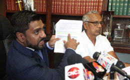 Attorney Gerald Ramdeen displays a document during a press conference at his law chambers on Cornelio Street, Woodbrook on Wednesday. At right is Baliram Ramdial, president of the combine four Cane Farmers Associations. 