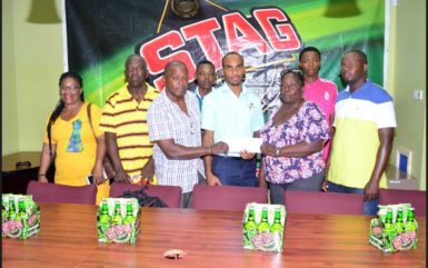 Stag Beer Brand Manager Linden Henry (centre) handing over the sponsorship cheque to WDFA President Orin Ferrier and Vice President Christine Schmidt while members of the participating teams look on. 