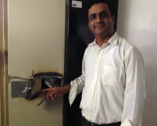 Chief Executive Officer of the Alesie Group of Companies Jai Keswani pointing to a lock on a metal cabinet that the bandits torched