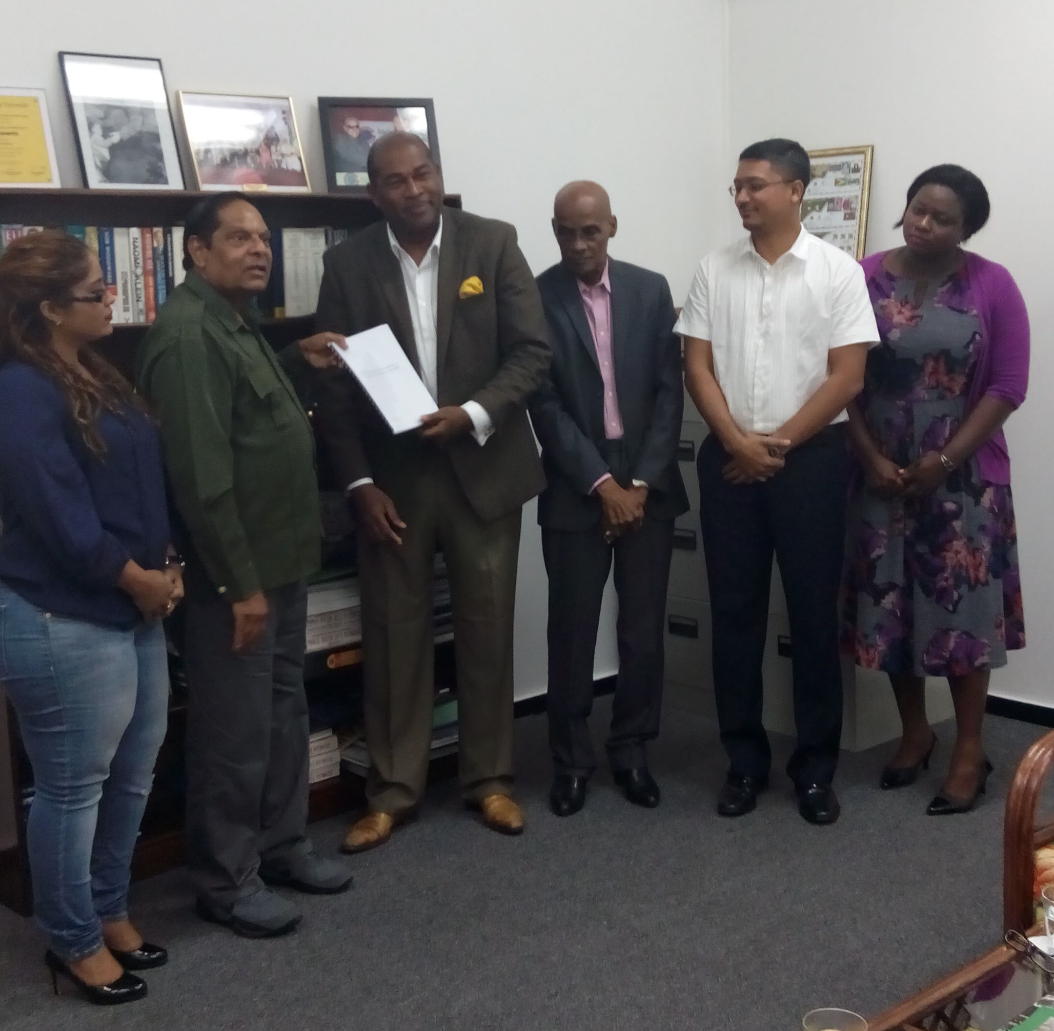 Prime Minister Moses Nagamootoo receives the final report from Convenor Nigel Hughes in the presence of from left: Geeta Chandan-Edmond, Professor Duke Pollard, Gino Persaud and Tamara Khan. Chandan-Edmond and Persaud are members of the Steering Committee while the others would have provided support. 