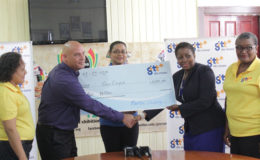 In photo at extreme left and right respectively are GTT PROs Nadia De Abreu and Allison Parker while GTT Marketing Director Daniel Jilesen (second from left) presents the cheque to Dawn Holder, Chairperson, GuyExpo Committee. At centre is GuyExpo Coordinator Tameka Sukhdeo-Singh. 