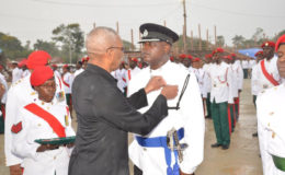 President David Granger, who is also Commander in Chief of the Armed Forces, pins a medal on an officer of the Guyana Police Force. (Ministry of the Presidency photo)
