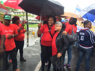 Ministers in the Ministry of Finance and Public Infrastructure, Jaipaul Sharma and Annette Ferguson sharing an umbrella at yesterday’s rain-soaked May Day.