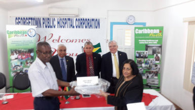 Chief Executive Officer (ag) of the Georgetown Public Hospital Allan Johnson (left) receiving a piece of equipment from Vice President of Caribbean North Charities Foundation Pamela Harakh yesterday. In the back row from left are: President of the foundation Harry Harakh, Minister of Public Health Dr George Norton and Pierre Giroux, Canadian High Commissioner