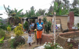 Rita and one of her children standing in front of her house