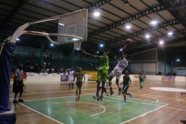 Timothy Thompson (green) of the Bishops High attempting to block Marian Academy’s Jordan Alphonso (white) during their matchup at the Cliff Anderson Sports Hall in the National School Basketball Festival (NSBF) Georgetown & East Coast Regionals 