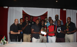 Captain of the Colts Basketball team Dave Causway (centre) is all smiles as he receives the tourney winnings from Mackeson Brand Manager Jamaal Douglas while other members of the team look on and display their respective accolades 