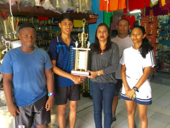 Ms. Devi Sunich of Trophy Stall, Junior Sportsman of the year Narayan Ramdhani, GBA Rep Marlon Chung and some Junior Players display some of the trophies that are up for grabs.