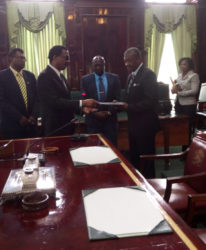 Attorney General and Minister of Legal Affairs Basil Williams (left) hands over a copy of the CoI report to Speaker of the National Assembly Dr. Barton Scotland.  (GINA photo) 
