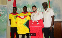 Golden Jaguars Captain Colin nelson (2nd from left) and Canada’s Captain Maxime Crépeau (2nd from right) displaying the signed team jerseys featuring the complete team rosters ahead of their historic showdown while other members of the respective teams inclusive of Guyanese Dwight Peters (left) look on.