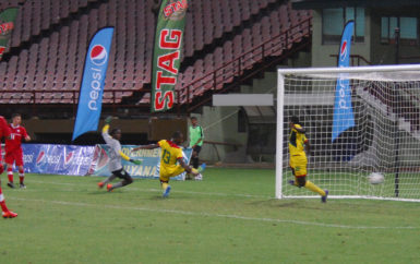 Canada’s Ben Fisk (no.11) in the process of scoring his side’s fourth goal despite the desperate attempts by the Guyana backline at the National Stadium in Providence. (Orlando Charles photo) 