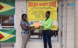 Payless Variety Store’s representative, Shonel Blackman presents a sponsorship cheque to one of the organizers, Avril Black yesterday in front of the Robb and Charlotte Streets entity. 
