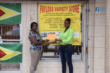 Payless Variety Store’s representative, Shonel Blackman presents a sponsorship cheque to one of the organizers, Avril Black yesterday in front of the Robb and Charlotte Streets entity.  