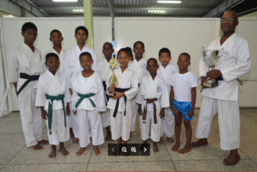 Sensei Winston Dunbar and Sadella Britton holding trophies, with some of the participants. 
