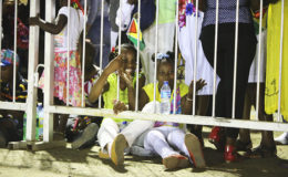 Two children enjoying their seats on the ground as the stands could not accommodate them.
