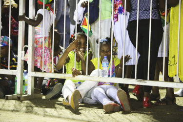 Two children enjoying their seats on the ground as the stands could not accommodate them. 