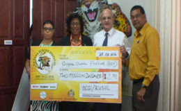 Minister of Public Telecommunications Catherine Hughes (second from left) receives a cheque from Vladimir Permyakov (second from right) Head, Bauxite Company of Guyana/Rusal (GINA photo)
