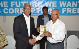 President David Granger (left) receives a copy of the book from Dr. Anand Goolsarran as Vice President and Minister of Public Security, Khemraj Ramjattan looks on. (Ministry of the Presidency photo)