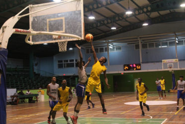 Nigel Bowen of Plaisance Secondary scores a layup while being challenged by a St. Stanislaus College player during their matchup in the U19 section of the National Schools Basketball Festival Georgetown and East Coast Regionals at the Cliff Anderson Sports Hall recently.