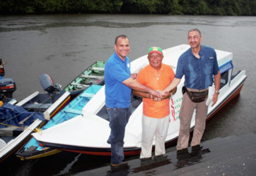 From left are CEO of Food for the Poor (Guyana) Kent Vincent, Toshao James Miguel and Managing Director of Courts Clyde De Haas during the handing over of a water ambulance intended to serve St Monica and Karawab. In the background is the new vessel.