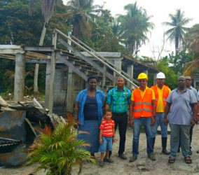 Fredrick James (second, right) with Amar Chetram and his brother (in construction vests), Vladimir Glasgow (second, left) and Mrs James (left) in front of the burnt house. 