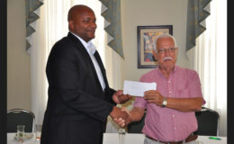 Former GABF President Joseph ‘Reds’ Perreira (right) handing over his donation to current GABF Chief Nigel Hinds following the conclusion of the press event staged at the Cara Lodge Hotel Monday.