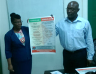 A member of the NCD alongside John Adams, advisor to the Minister of Social Protection, holding up a disability etiquette poster.  