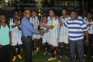 Victorious captain Javair Smith collecting the championship trophy from UDFA President Sharma Solomon while other members of the team look on after defeating Amelia’s Ward Panthers in the finale at the Mackenzie Sports Club ground 
