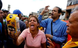 A woman shows a flour package outside a supermarket as they shout slogans over food shortage in Caracas, Venezuela, June 11, 2016. REUTERS/Ivan Alvarado/File Photo